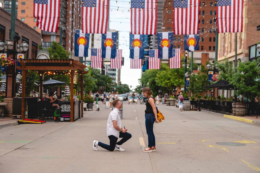 Brick-lined urban street decorated with American flags and blue banners displays classic downtown architecture.