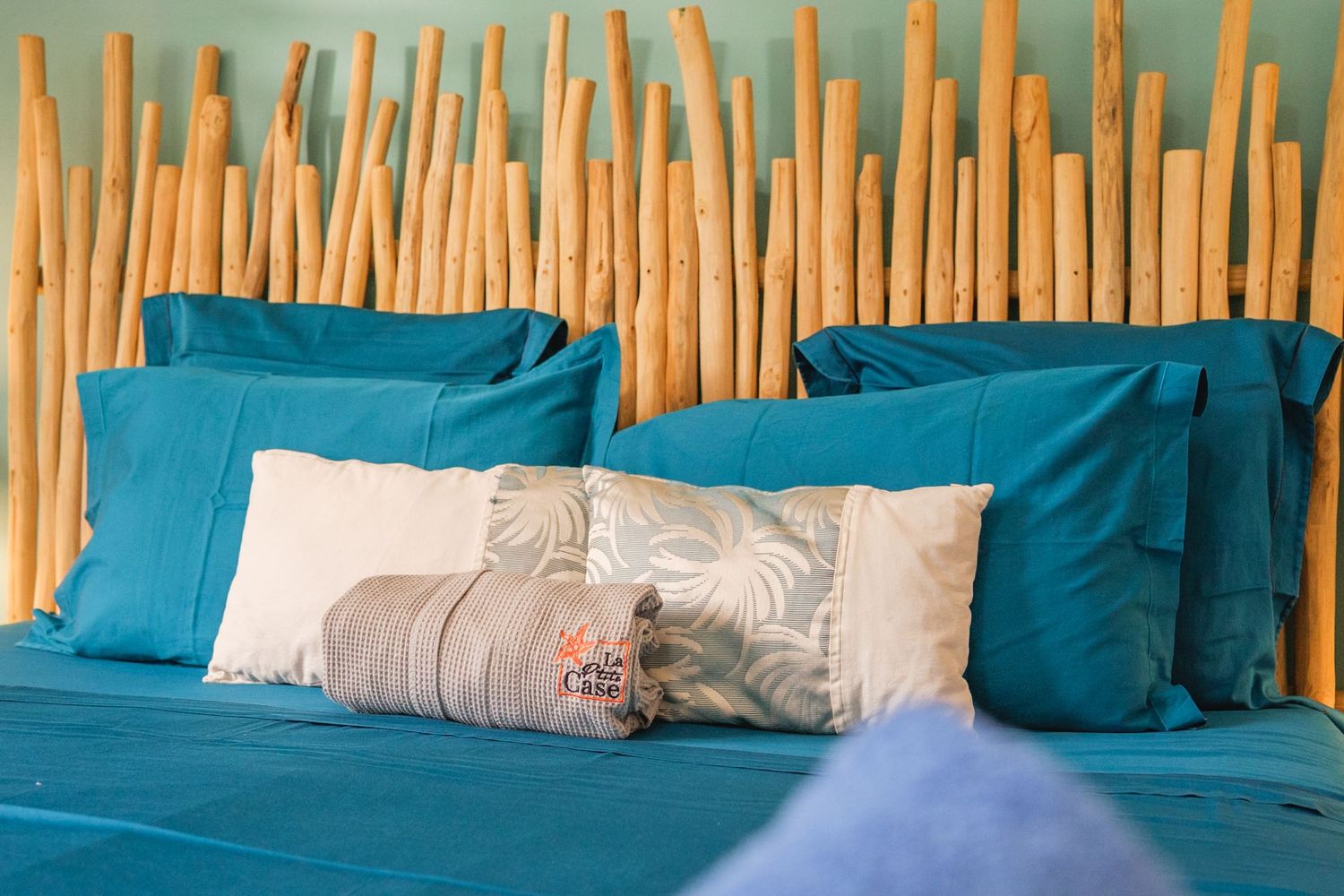 Wooden bamboo fence with turquoise blue cushions lined up against it creating a serene outdoor seating area.