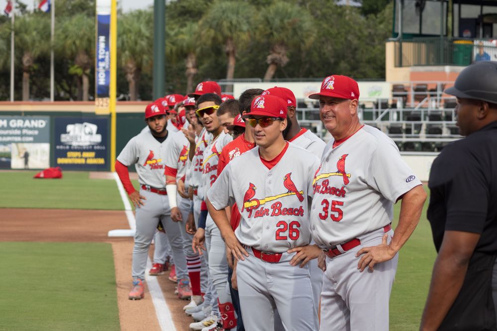 Baseball players in red and white uniforms gather on the field during a game.