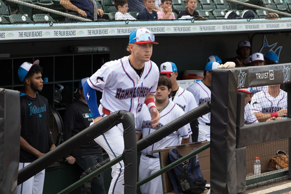 Baseball players and staff members interact in the dugout during a game.