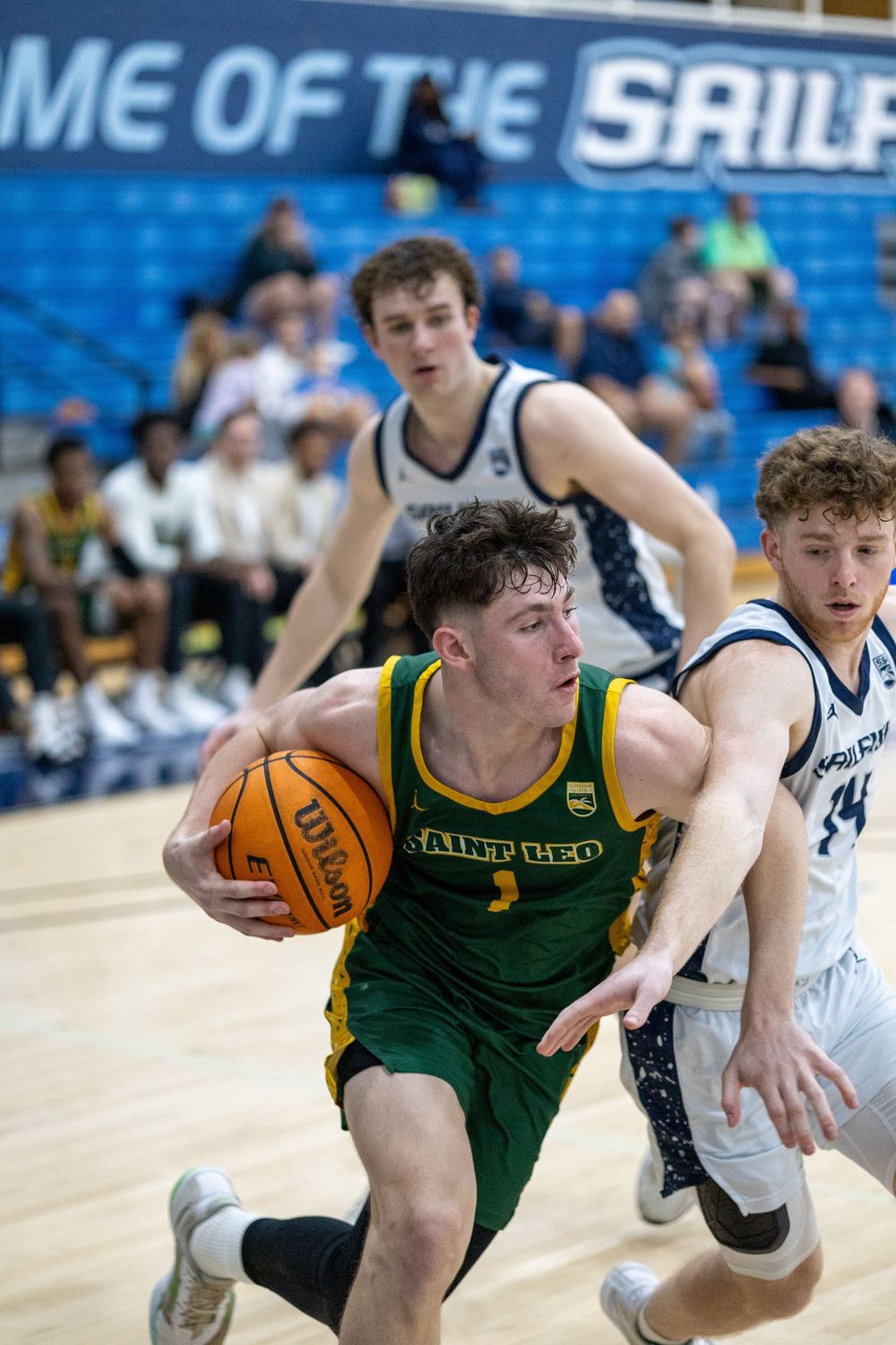Basketball player in green jersey drives to basket against defensive pressure.
