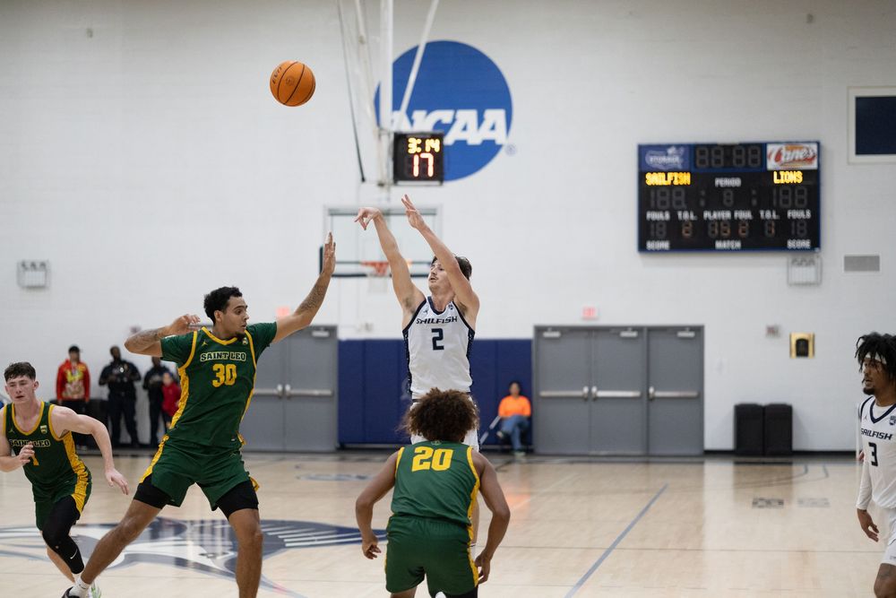 Players jump for basketball during competitive game action.