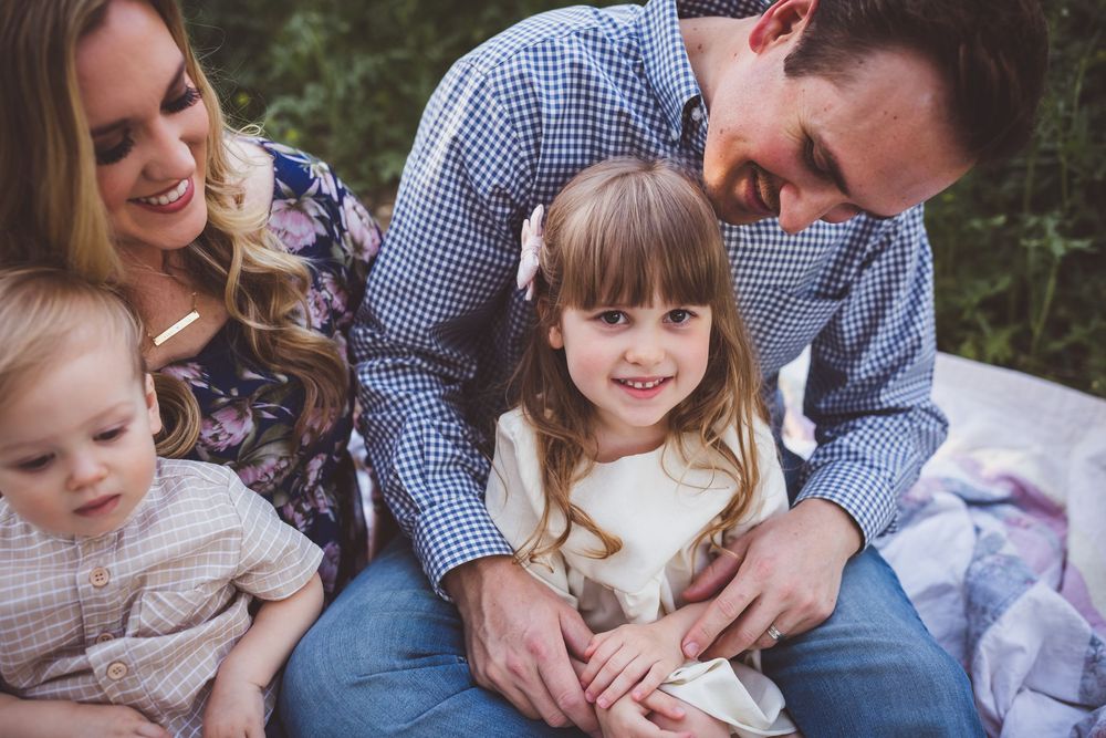 A series of intimate family moments captured outdoors showing parents and children embracing and playing together.