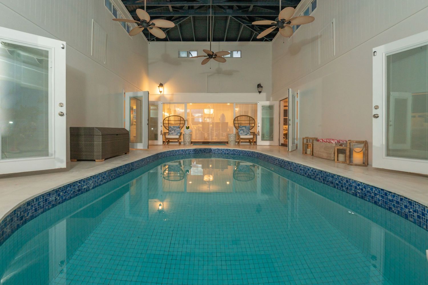 Long indoor swimming pool with blue water and stone accent tiles along the wall.