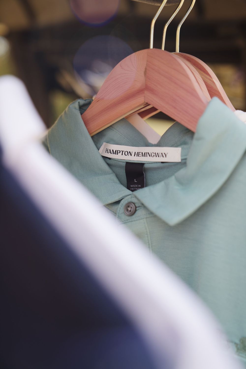 Close-up of mint green polo shirt collar on clothing hanger.