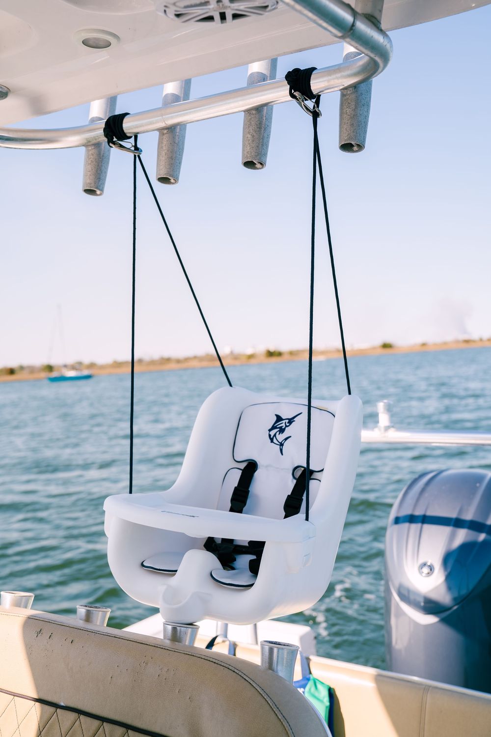 White boat seats mounted under a canopy on a vessel cruising across blue waters on a sunny day.