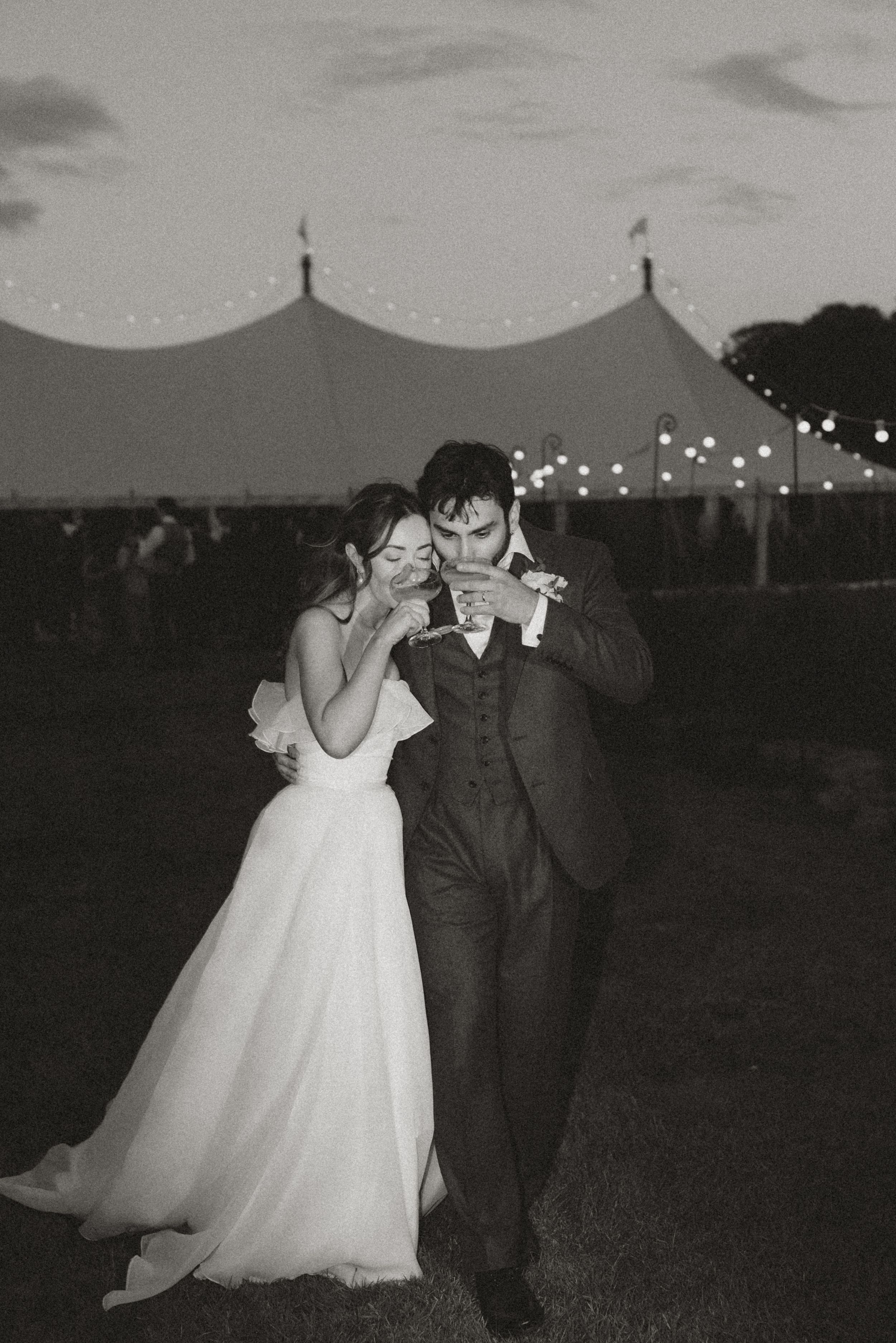 Black and white wedding photographs show a couple dancing with string lights illuminating the background at dusk.