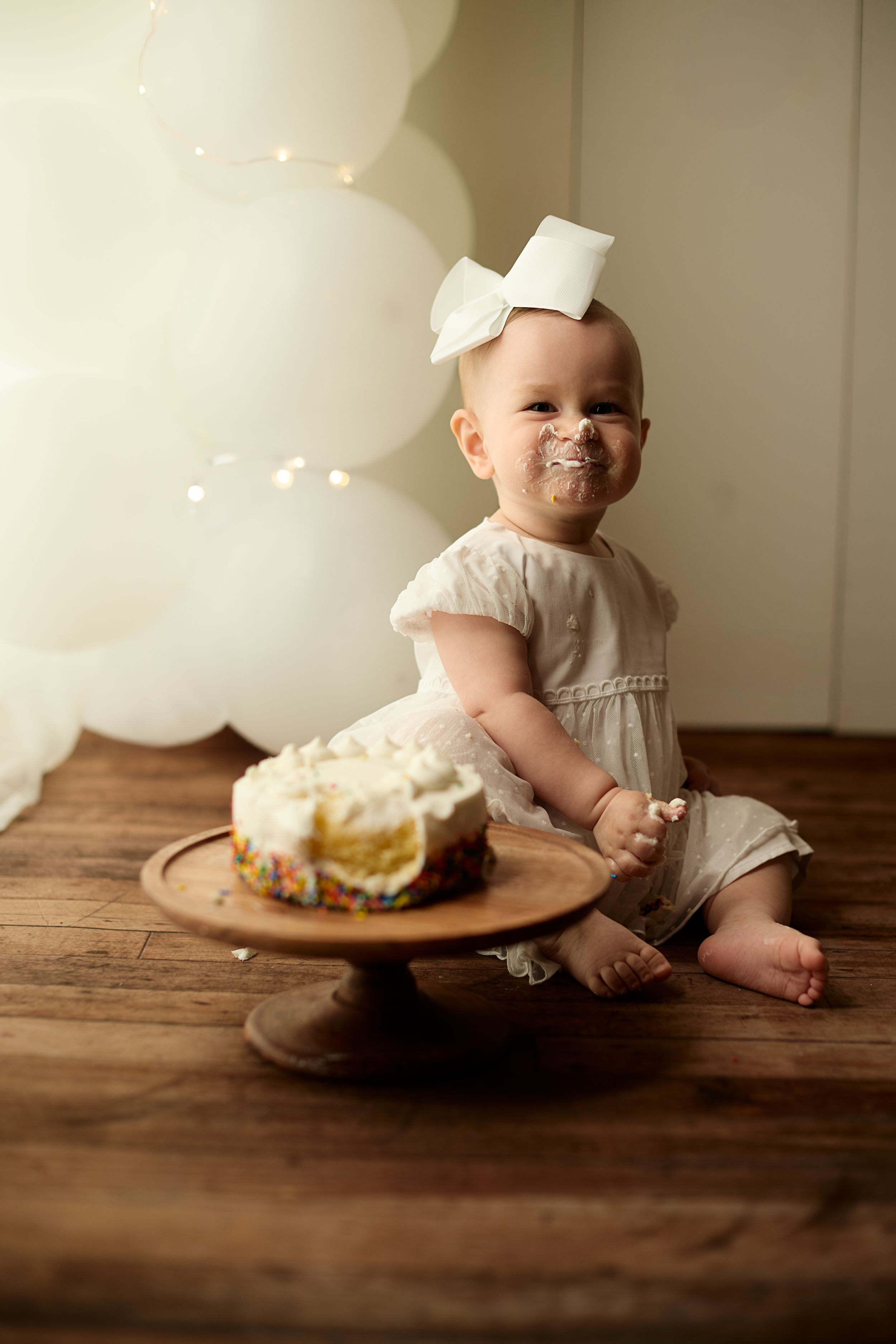 Series of photos showing an infant in a chef's hat doing a cake smash photoshoot on a rustic wooden table.