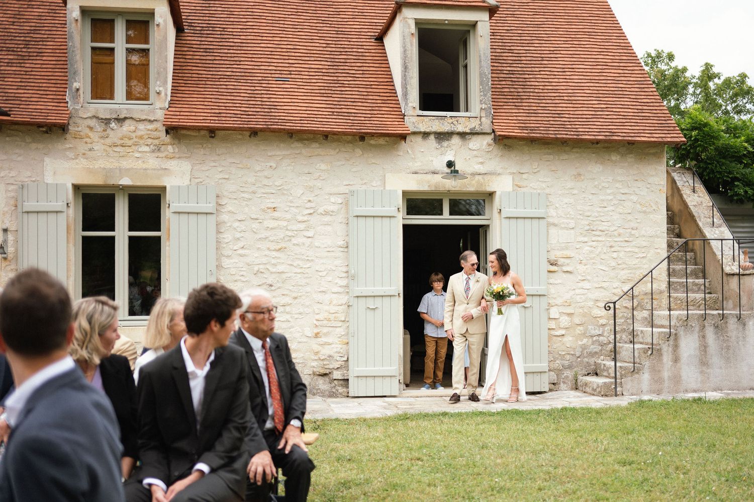 Entrée de la mariée accompagnée par un proche dans un domaine familial en Sologne – Amandine Derimay photographe