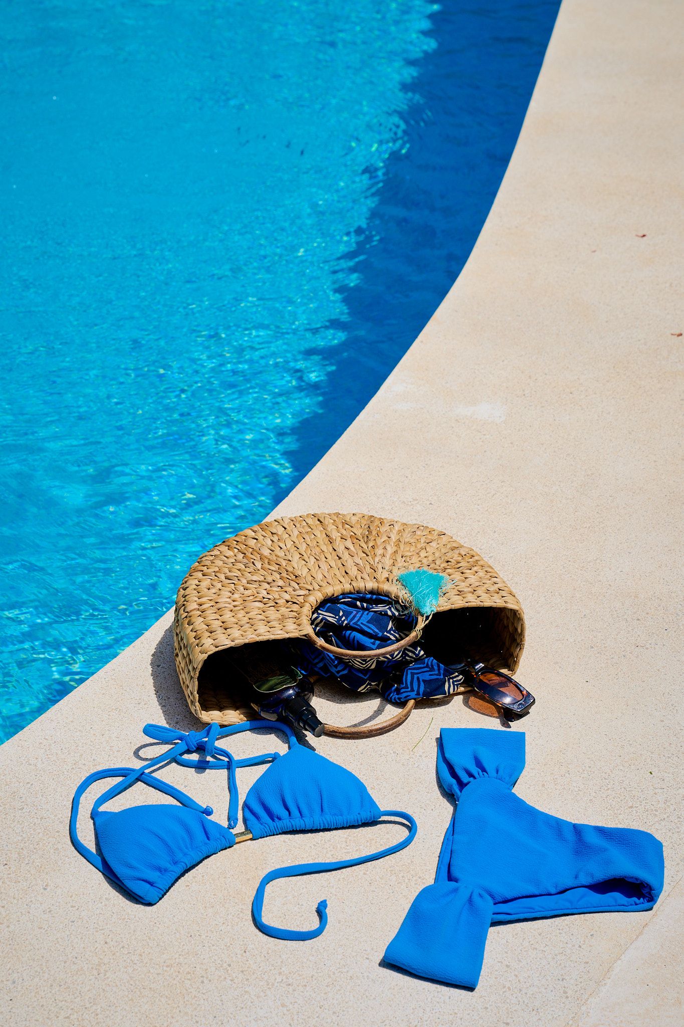 Four sequential images of a straw hat, sunglasses and blue bikini arranged beside a swimming pool.