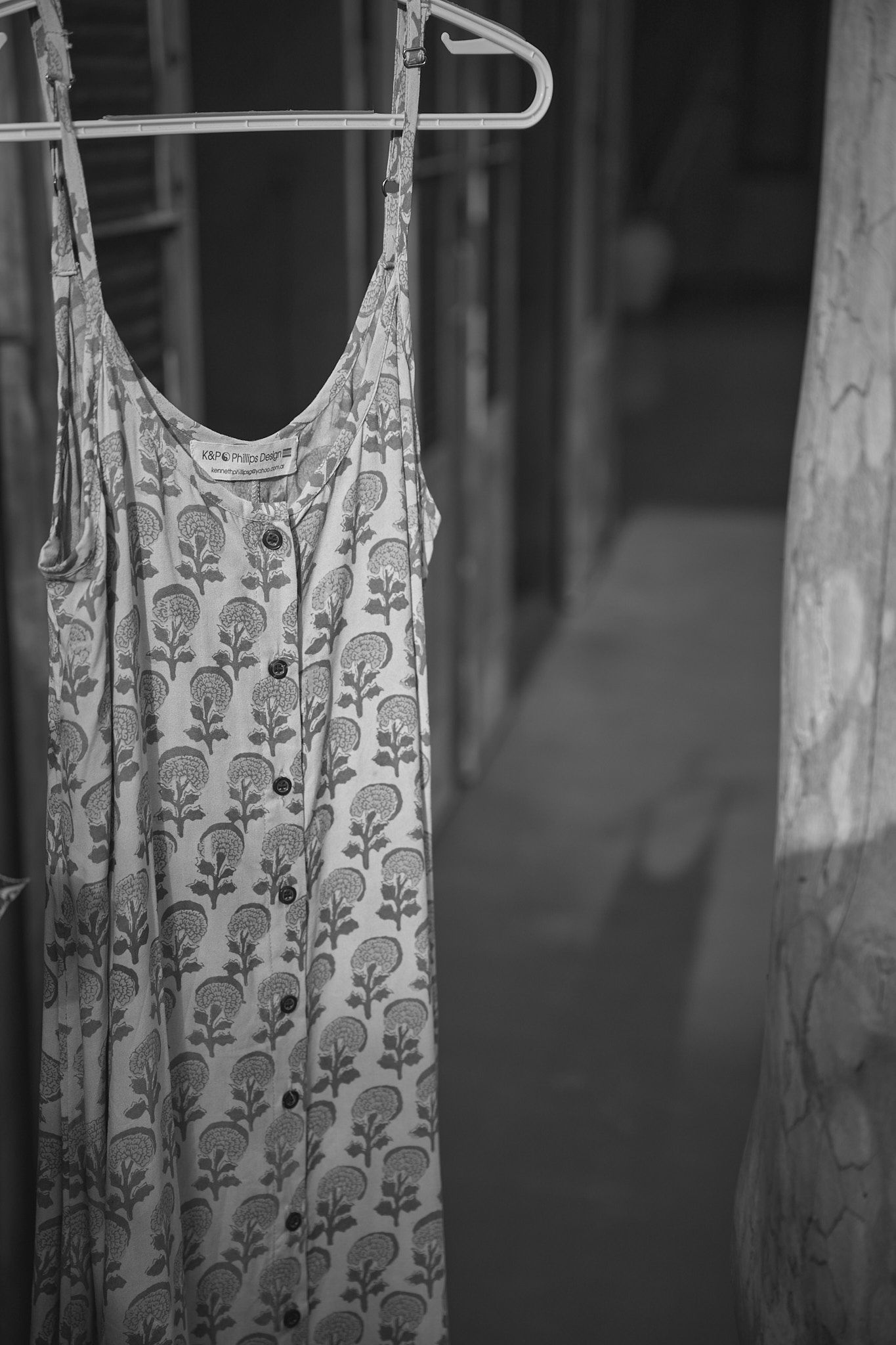 A floral patterned sundress hanging on a white plastic hanger against a dark background.