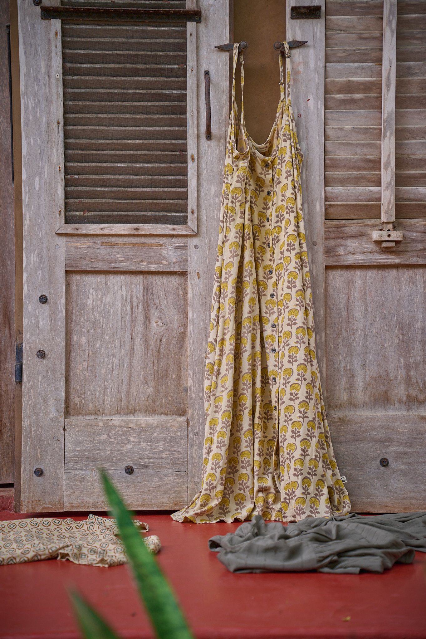 A panoramic shot shows wooden shutters on a wall with gold patterned fabric draped alongside a red floor.