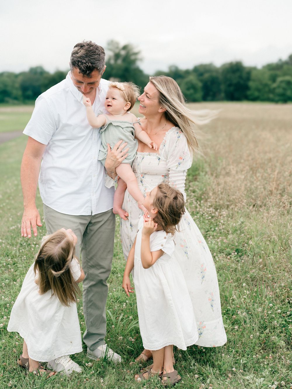 Candid photo of family of five cuddled together in a field — relaxed and joyful family photography in New Jersey.