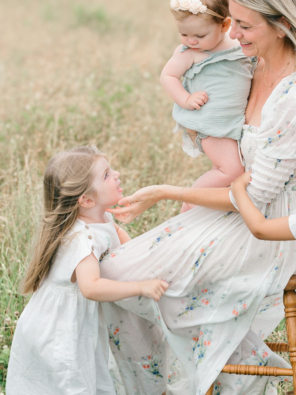 A mother touches her daughter's chin while sitting in a grassy open field in New Jersey.