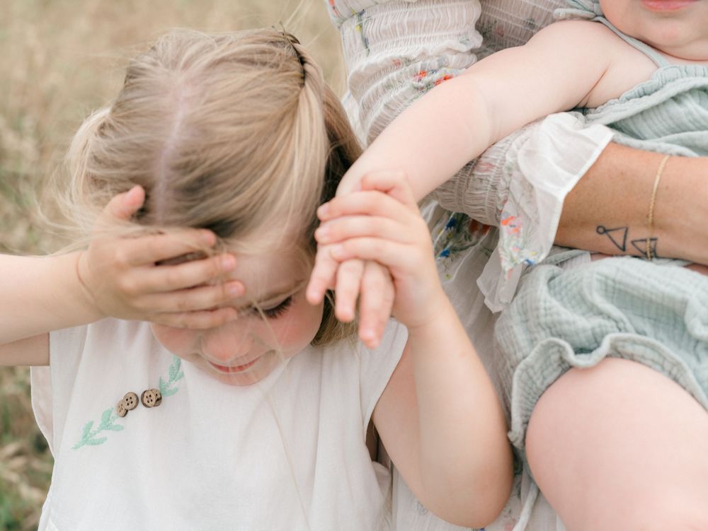 A young girl holds her sister's hand in a field in colts neck, New Jersey.