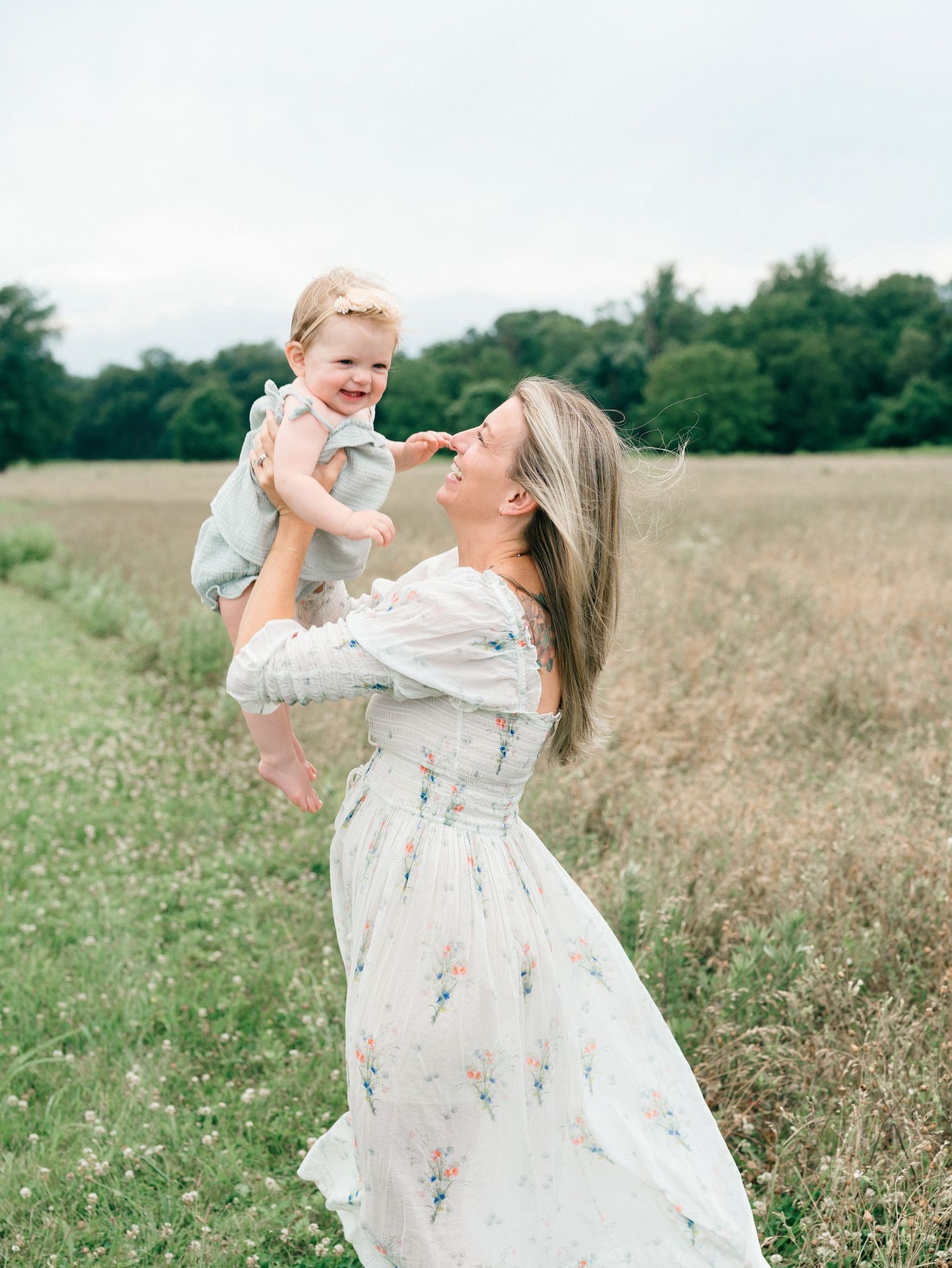 A mother lifts her daughter in the air with an open field behind her in colts neck NJ.