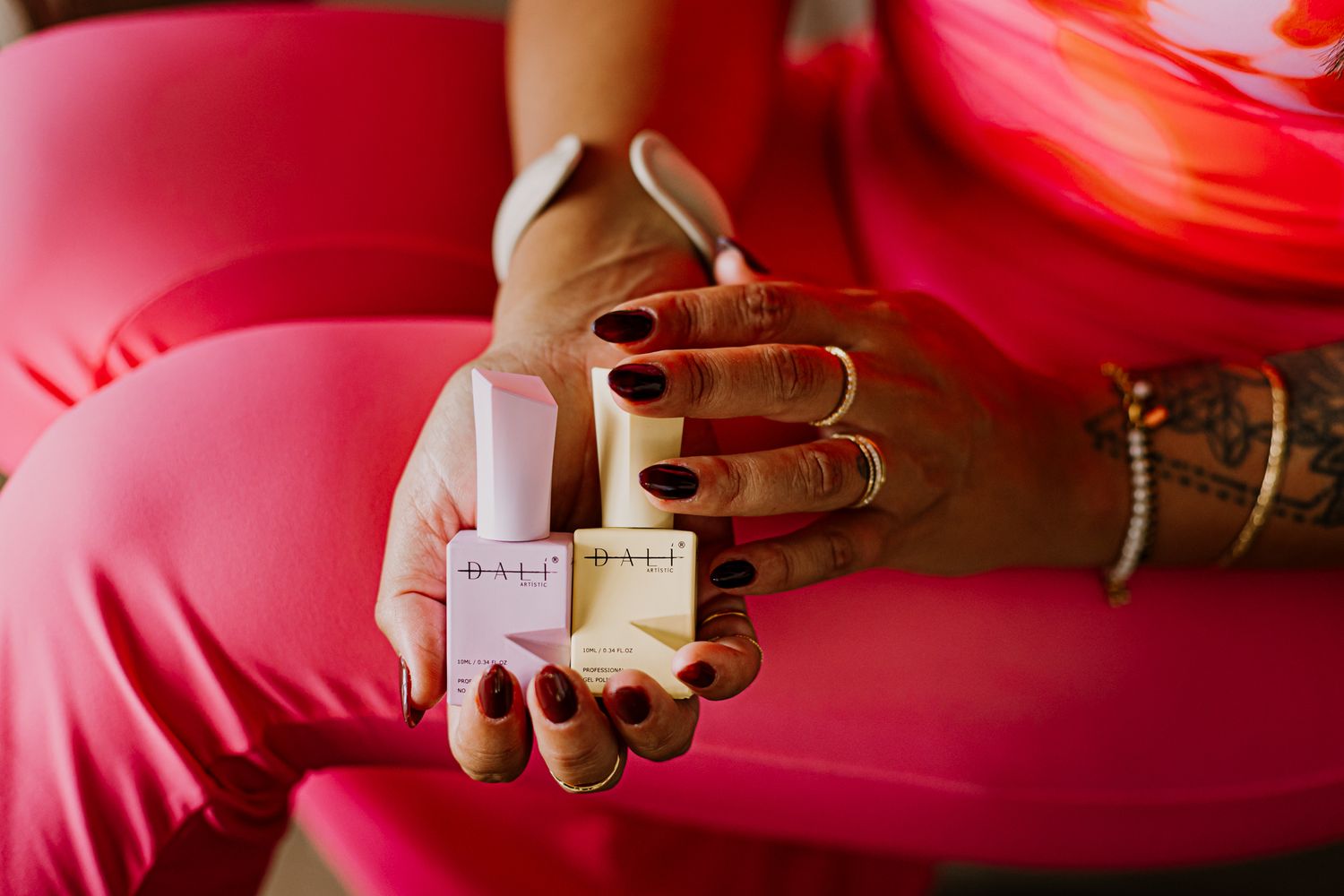 Two hands holds two nail polish products.