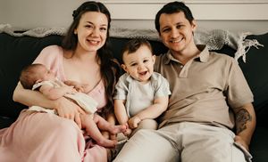 Candid family portrait shows parents with their children relaxing on a couch.