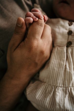 Close-up of parent's hand gently holding baby's tiny foot.