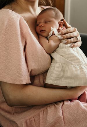 A tender nursing moment captured in soft pink tones shows nurturing closeness and care.