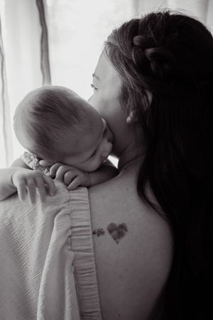 Intimate black and white portrait showing tender nurturing moment by window light.