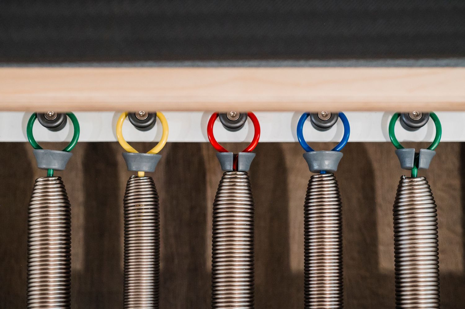 Dental tools with colorful handles and metal springs lined up in a row under a white surface.
