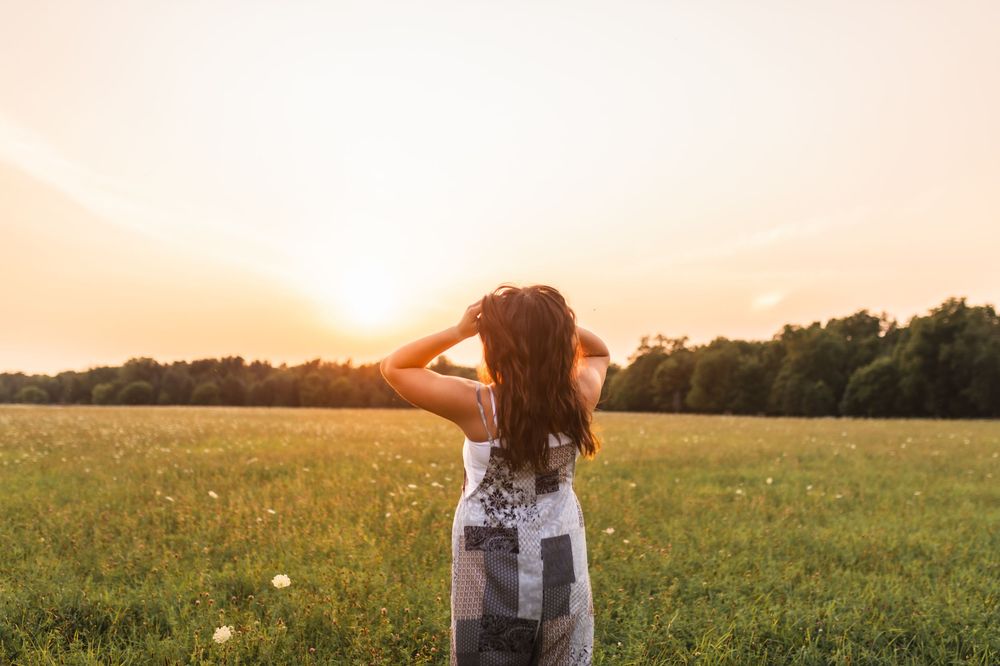 Candid shot of a senior girl watching the sunset during her photo session in an open field.