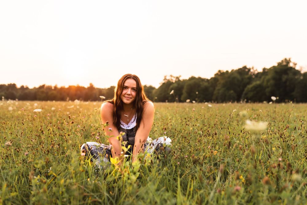 Soft backlit photo of a senior girl in an open field.