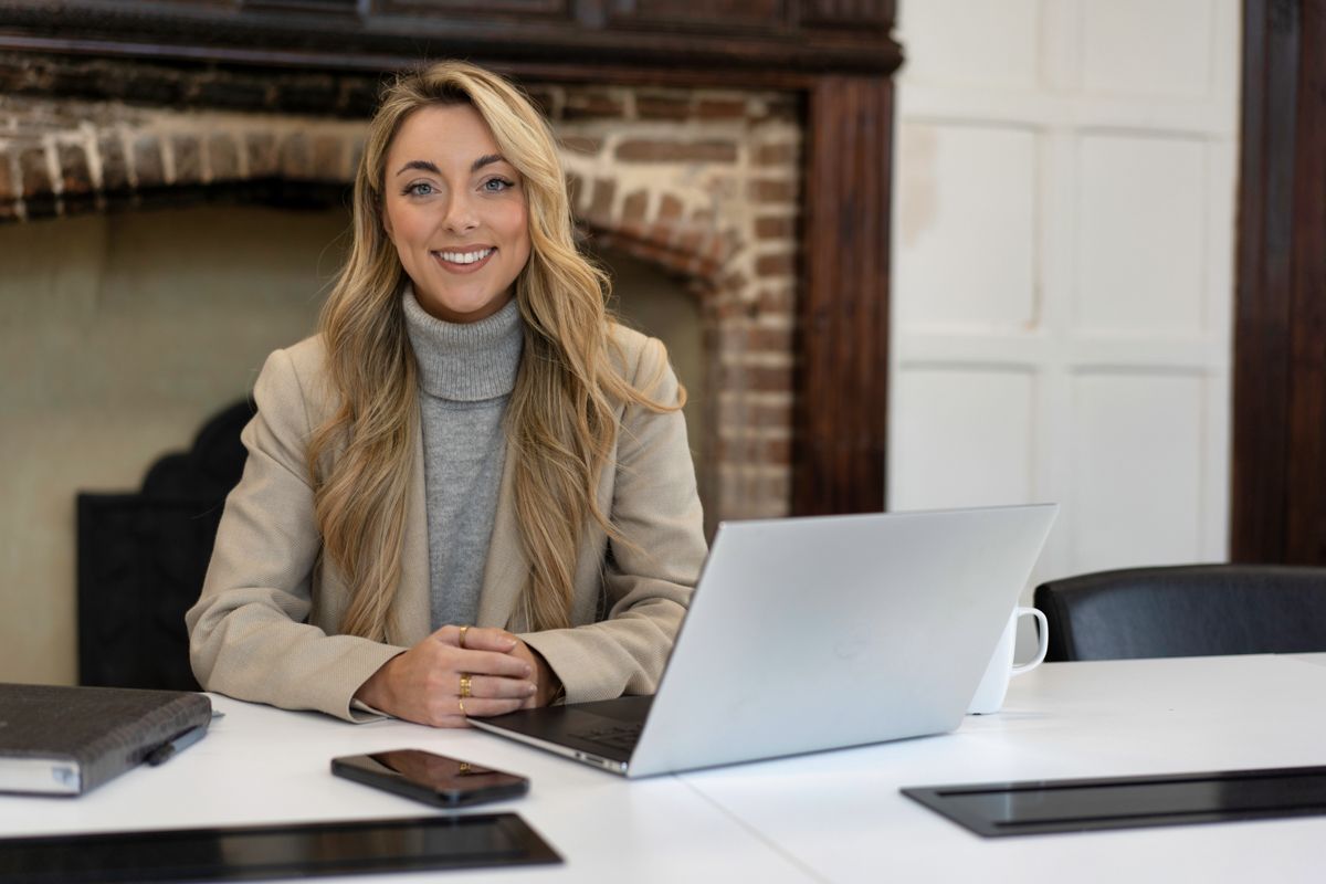 Professional sitting at desk with laptop computer in modern office environment with stone wall background.