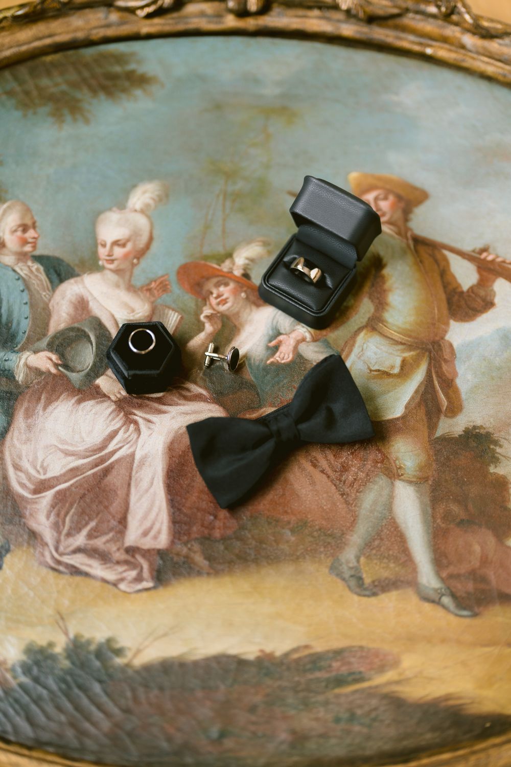 Wedding accessories arranged on vintage artwork featuring rings and bow tie. Photoshoot by Venice Photographer Alina Indi