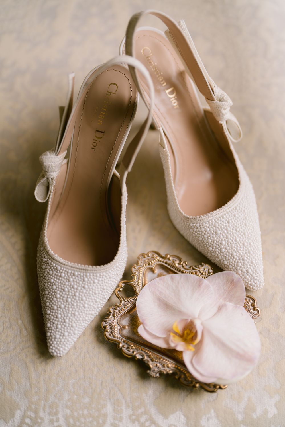 Elegant white beaded bridal shoes with delicate orchid detail on vintage frame. Photoshoot by Venice Photographer Alina Indi
