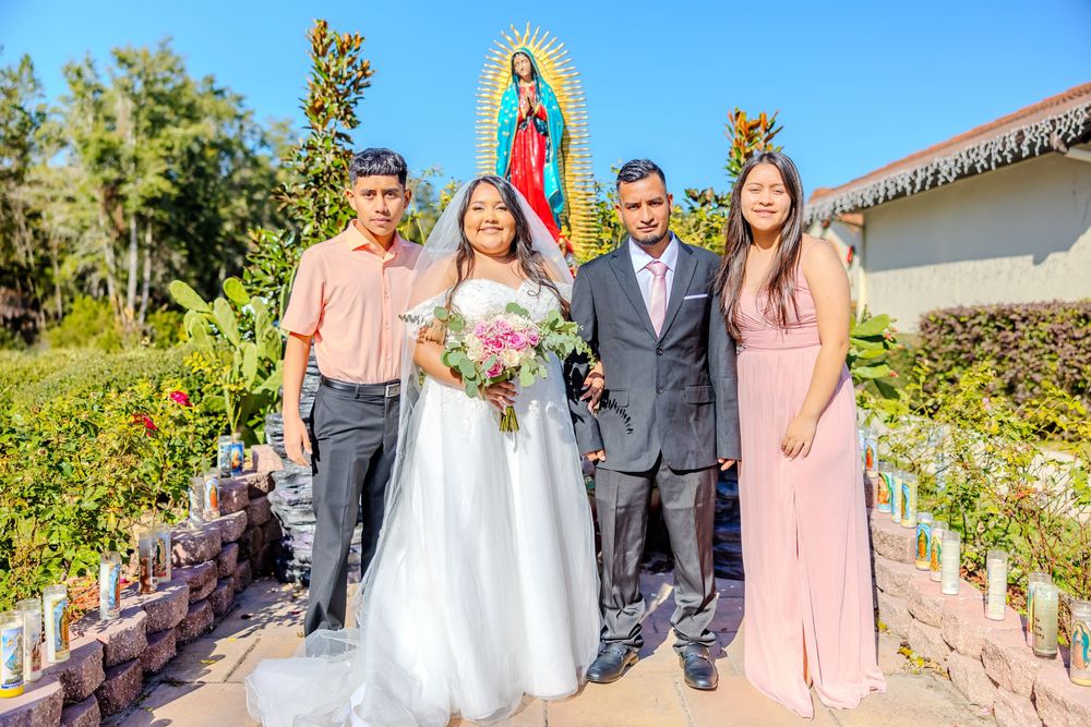 Bridal party gathered for photos with Our Lady of Guadalupe statue in background.