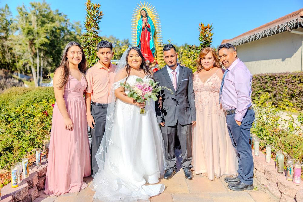 Wedding party lined up outdoors with pink and gray color scheme near church grounds.