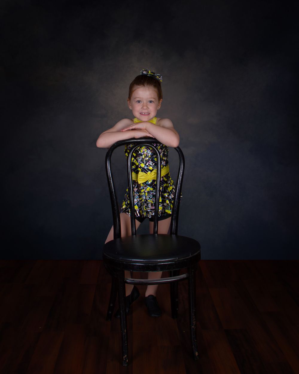 A sequence of photos showing a child seated in a dark wooden chair against a moody black background.