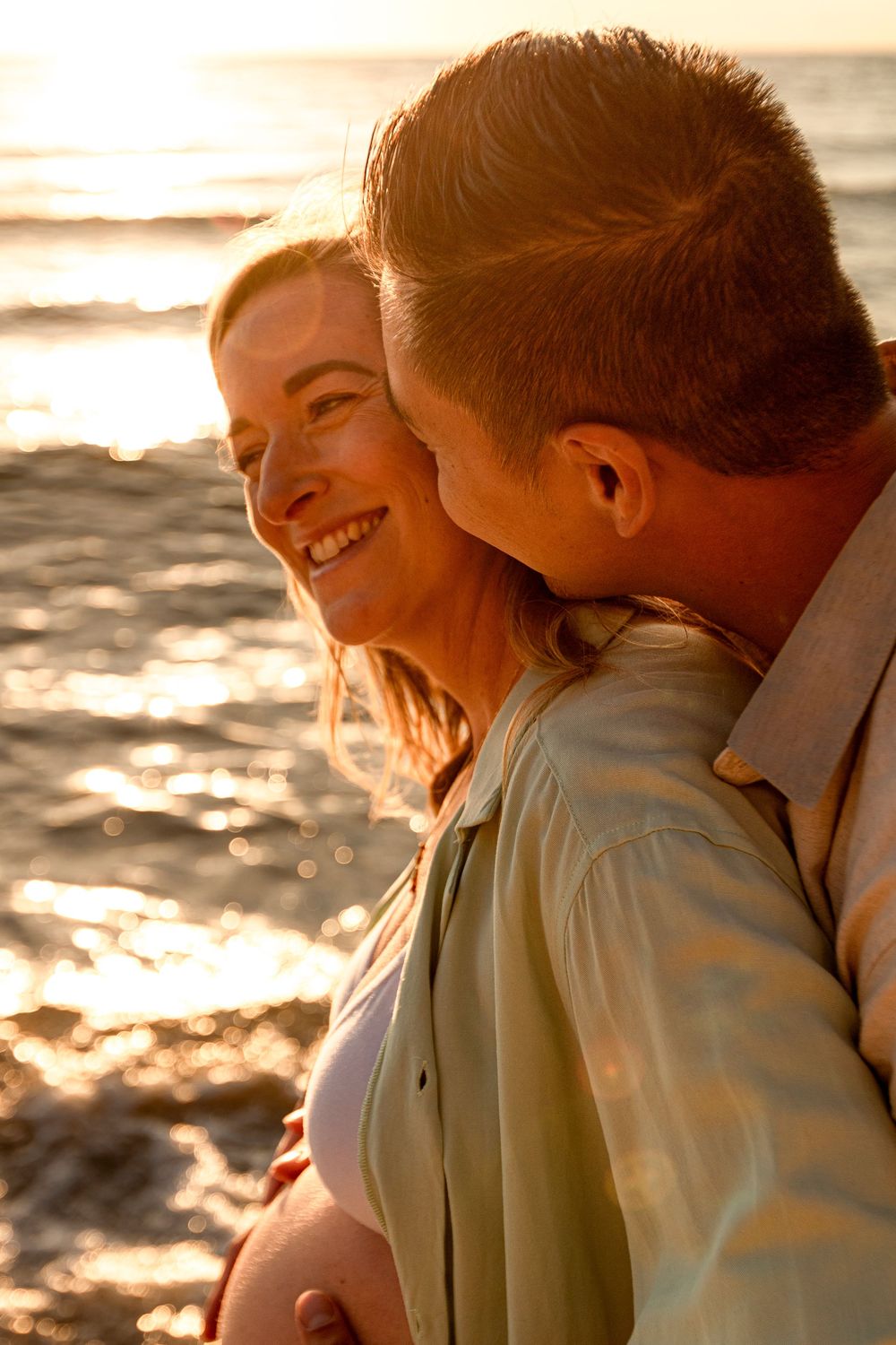 Intimate moment captured between couple during golden hour beach maternity session.