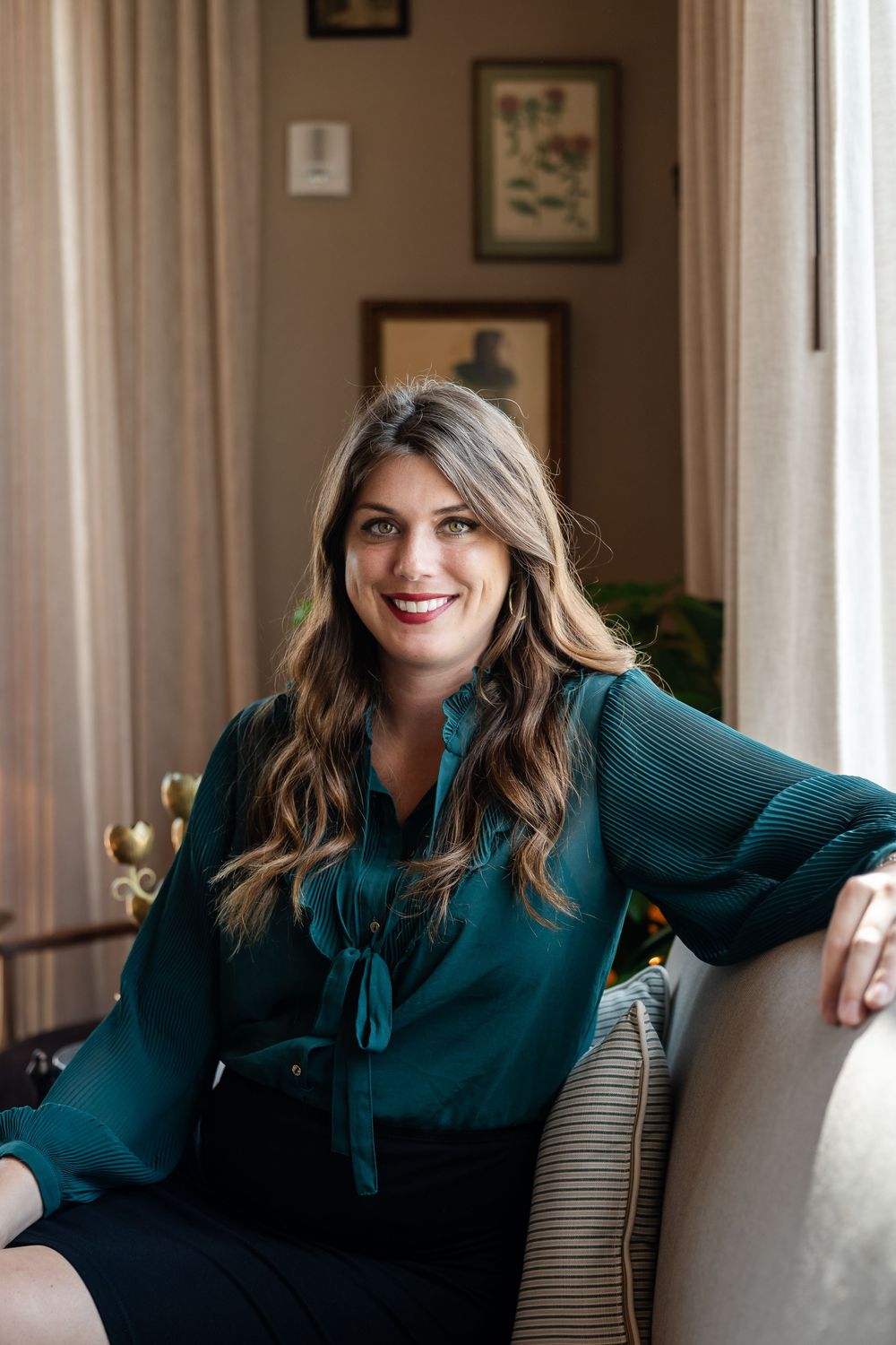 Lifestyle portrait of woman in teal blouse relaxing on couch in home setting.