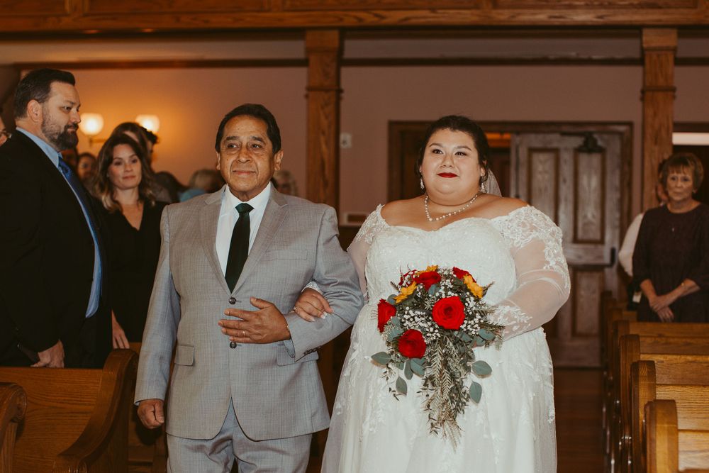 Wedding ceremony taking place in a church with stained glass windows and wooden interior.