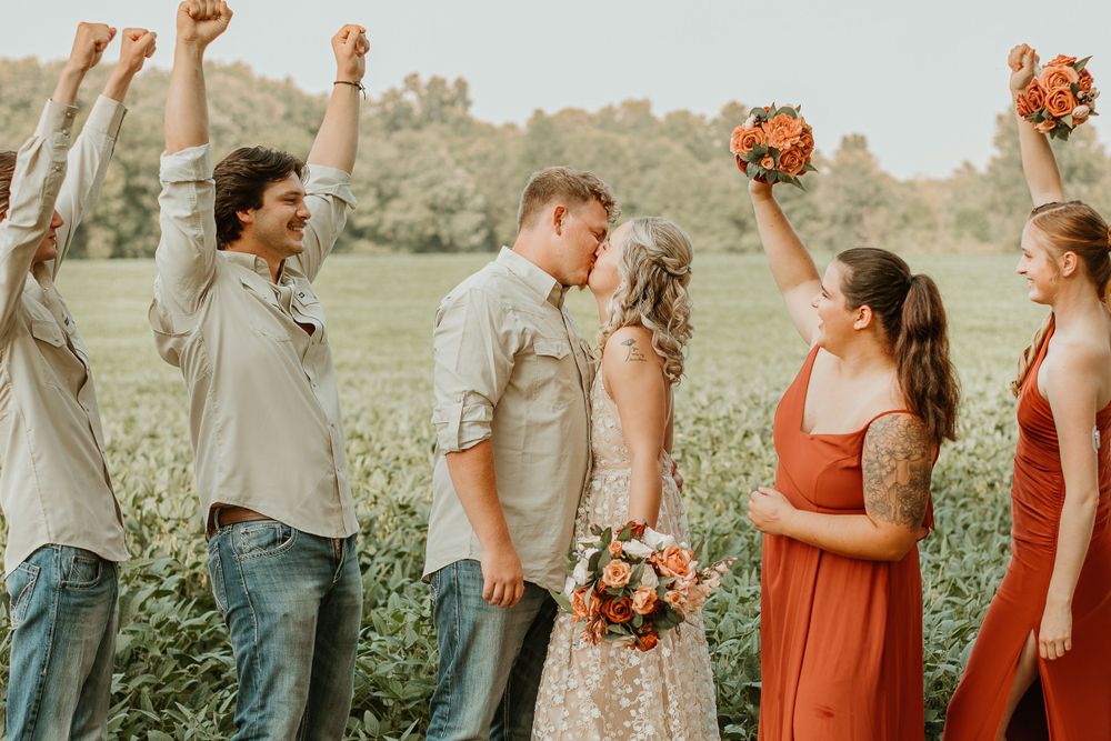 Wedding party members celebrating and laughing together in an outdoor setting.