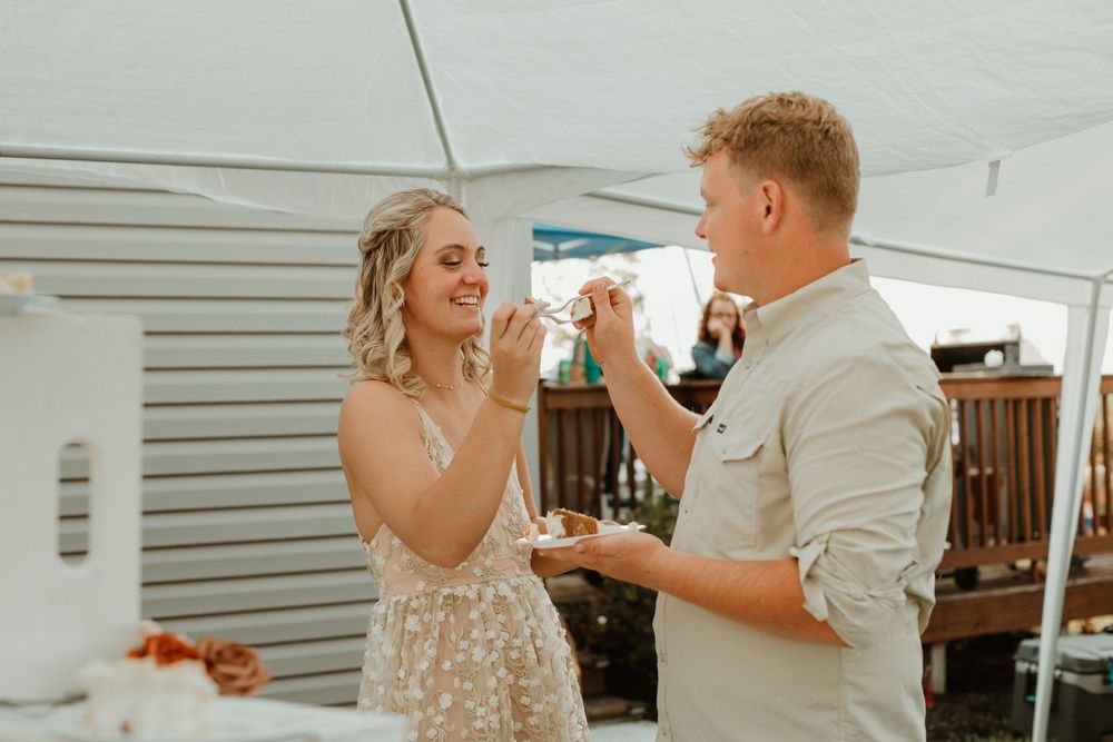Wedding celebration under a white tent with people dancing and enjoying cake.