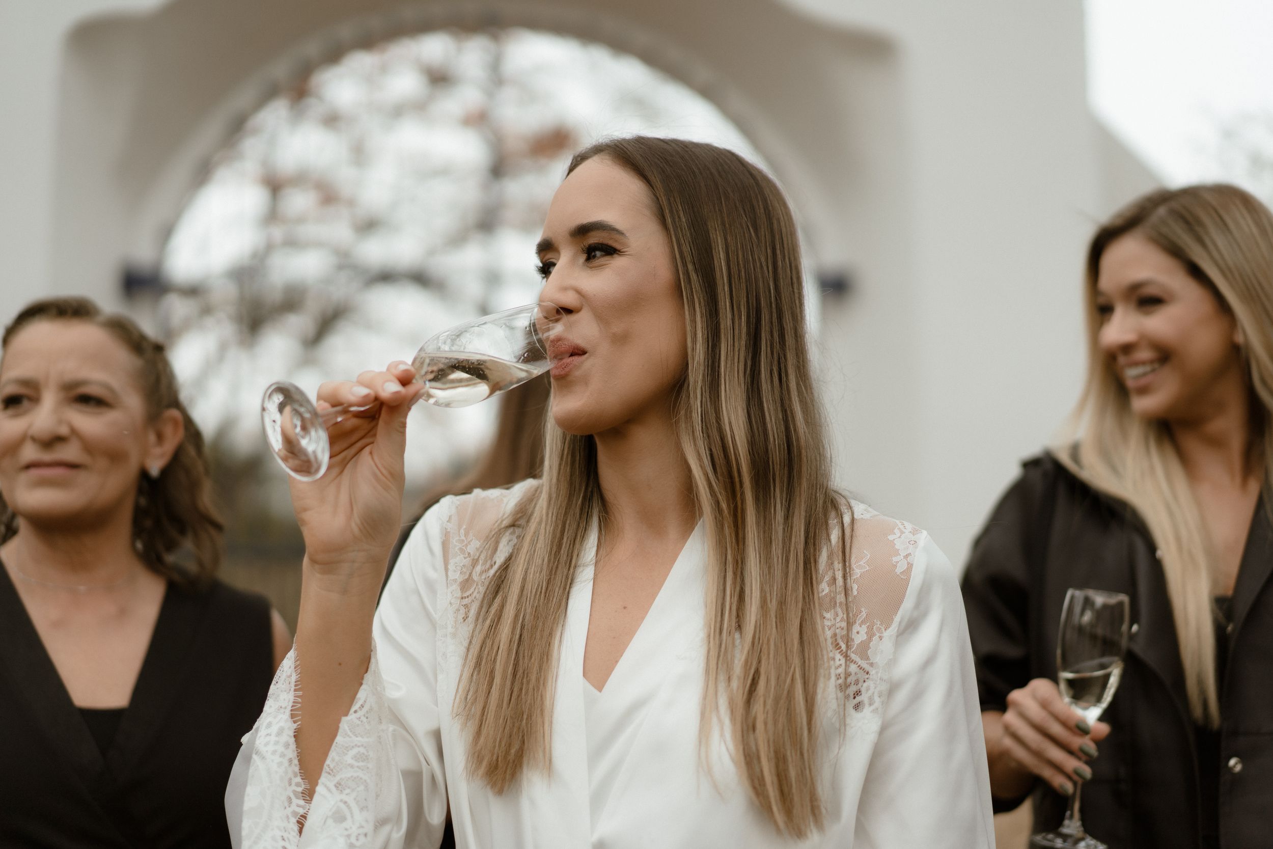 A group of women in formal attire enjoying drinks at a party.