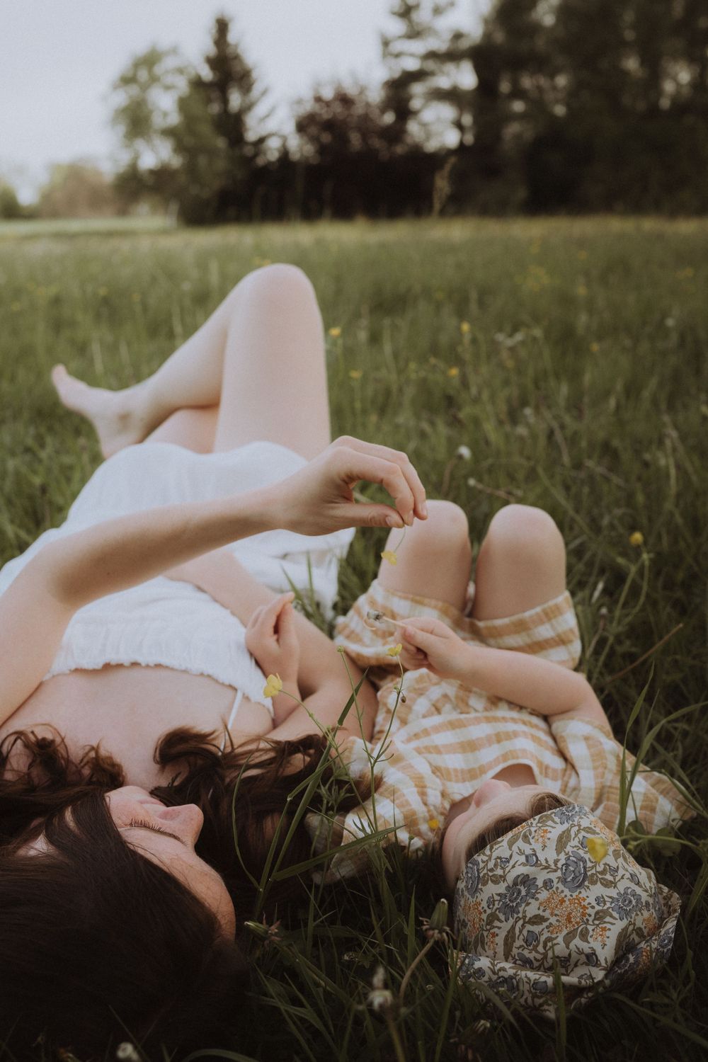 Two people lying in a sunny meadow wearing white and gingham outfits.