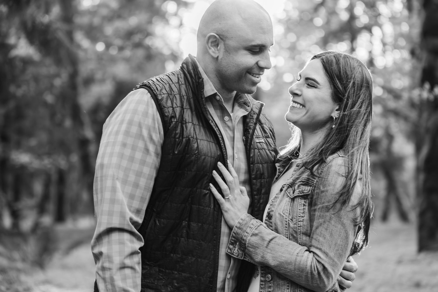 A romantic black and white engagement photo of a couple sharing a joyful moment outdoors.
