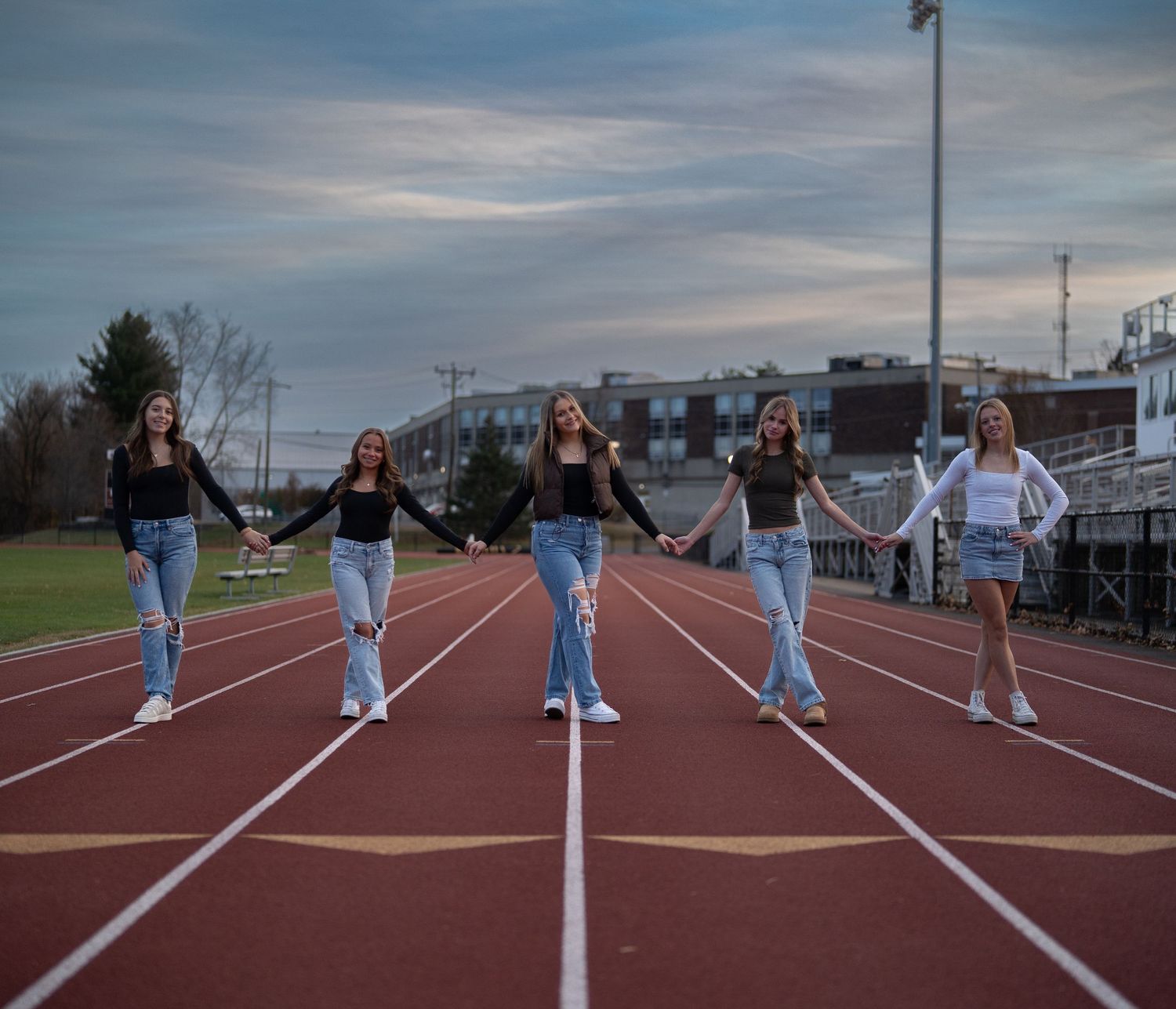 Group lined up on running track lanes in matching outfits for choreographed photo.