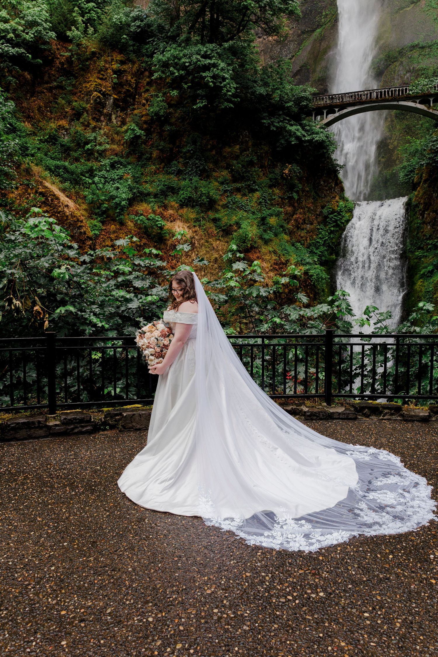 A person in a white wedding dress poses near Multnomah Falls in Oregon's Columbia River Gorge.