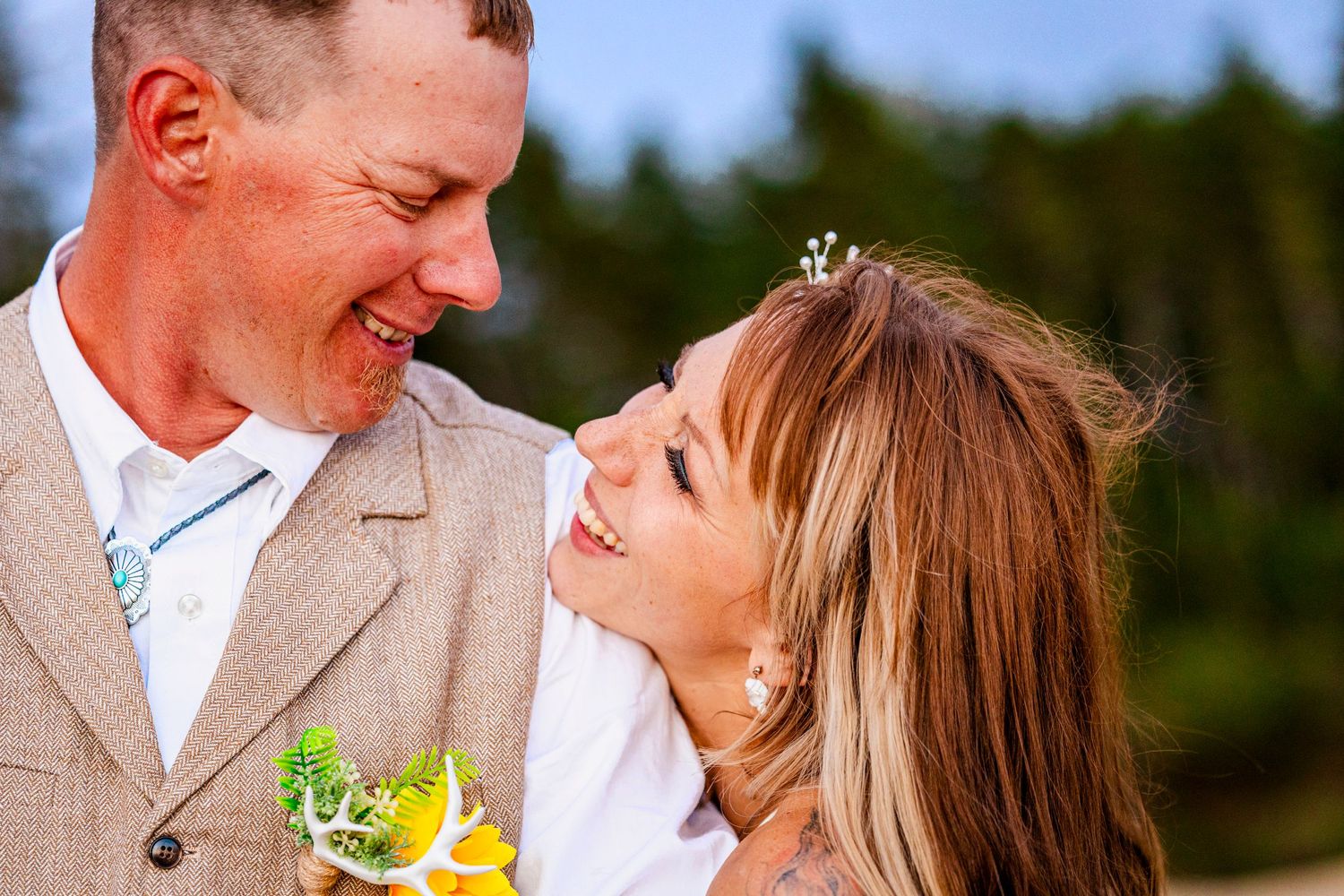 Happy newlyweds share joyful laughter during outdoor wedding photoshoot.