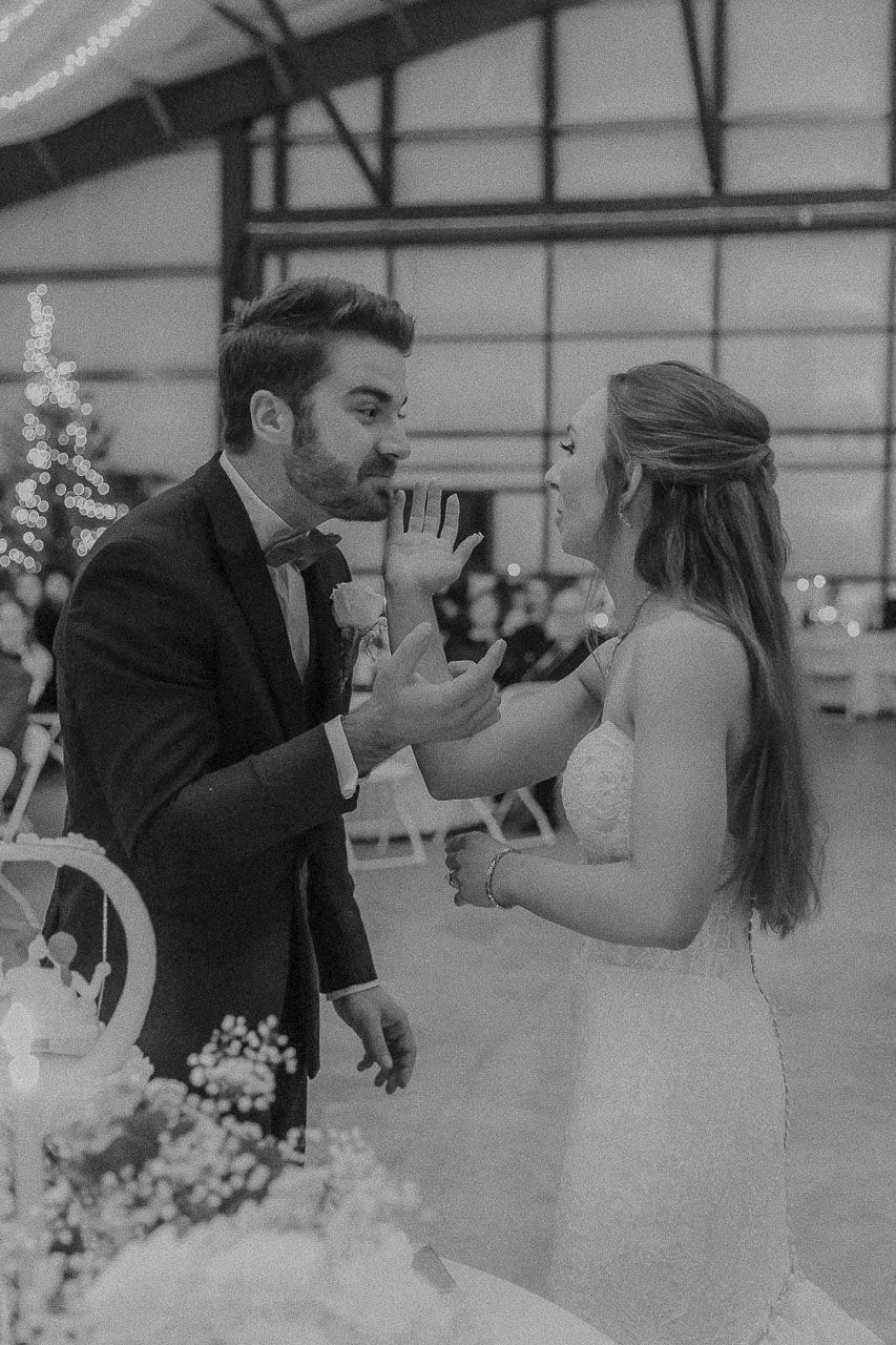 Black and white photo of a bride and groom sharing a milkshake together at their wedding reception.