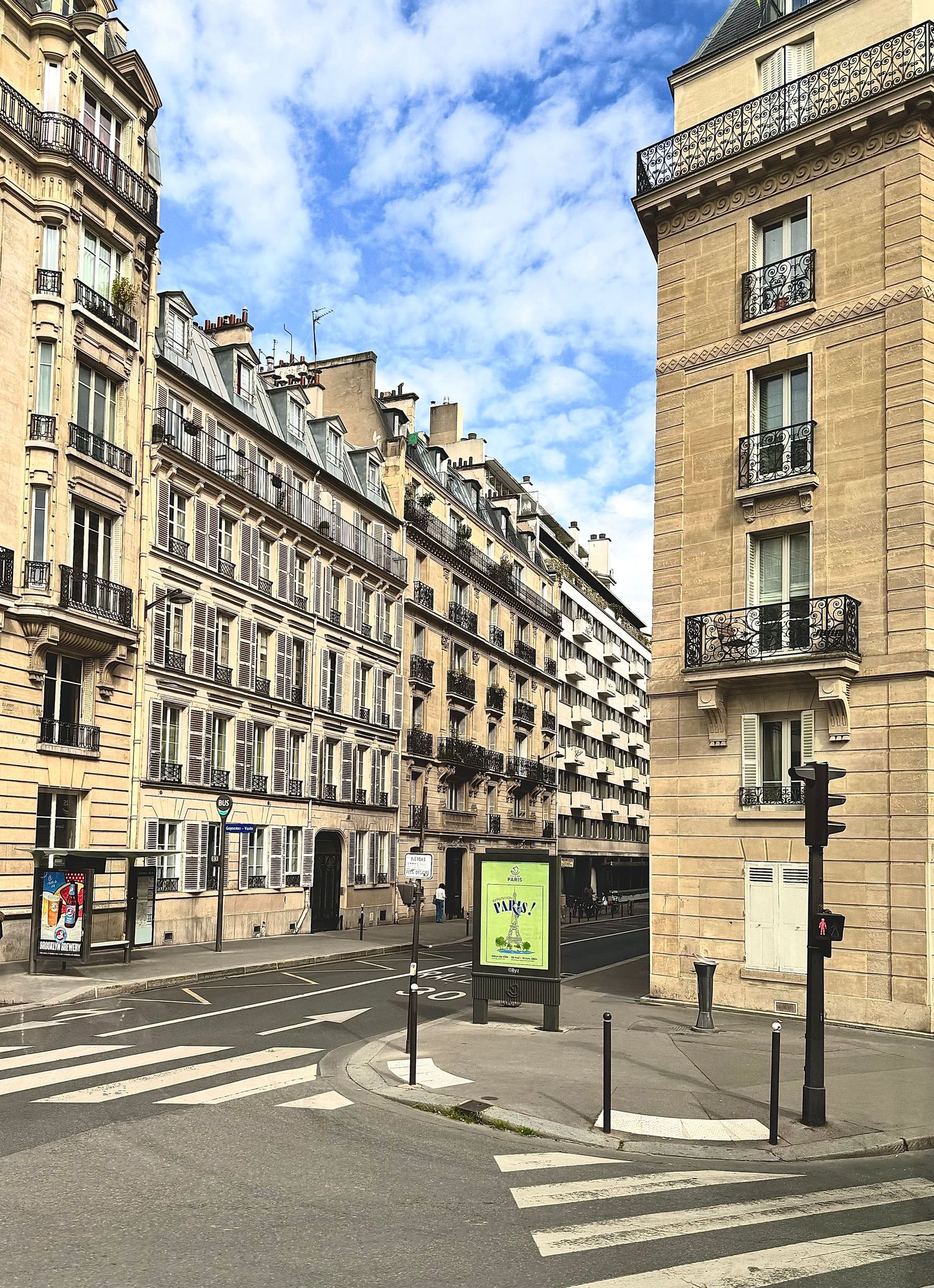Classic Parisian street with elegant Haussmanian buildings and blue sky overhead.