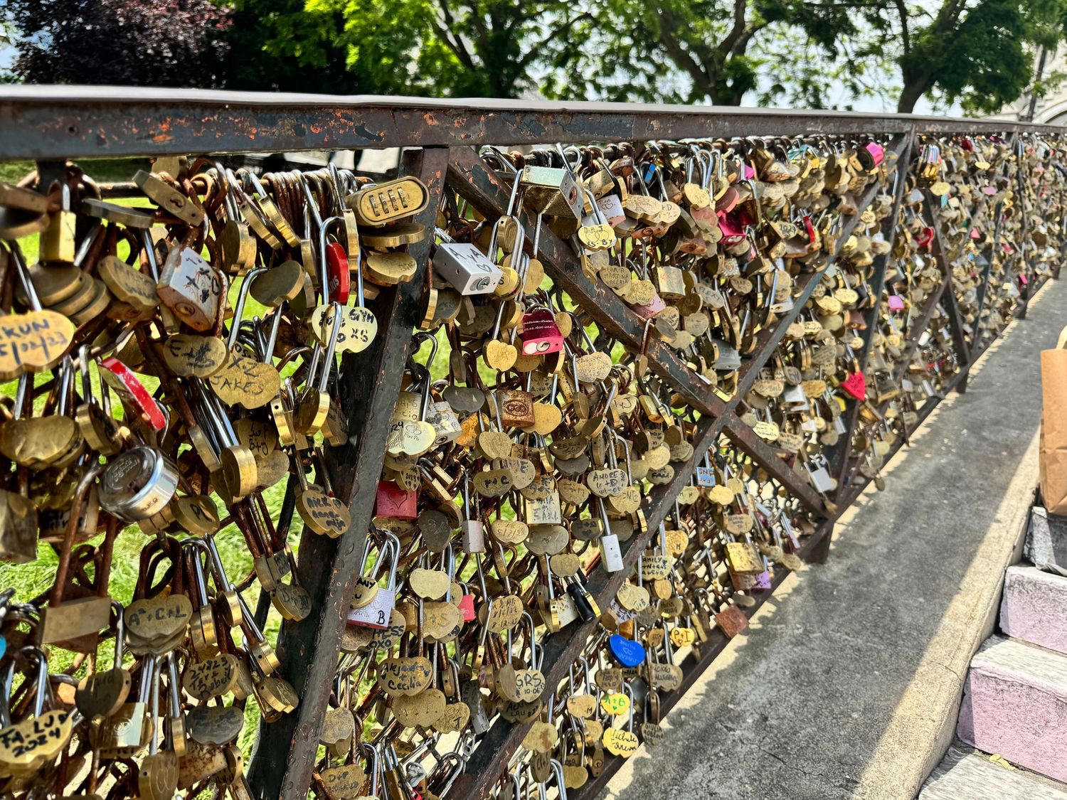 Love locks attached to bridge railing creating colorful pattern of metal padlocks.