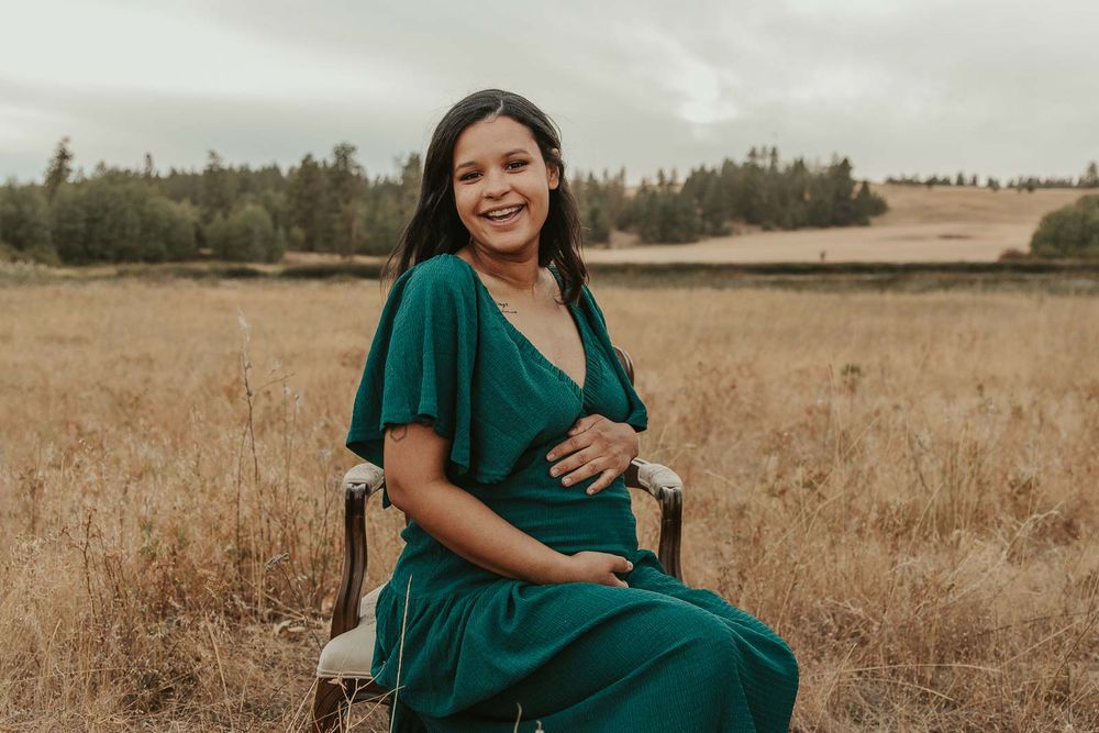 Golden hour maternity photo with Spokane maternity photographer Elishia Jackson, featuring a peaceful outdoor backdrop, mom giggling