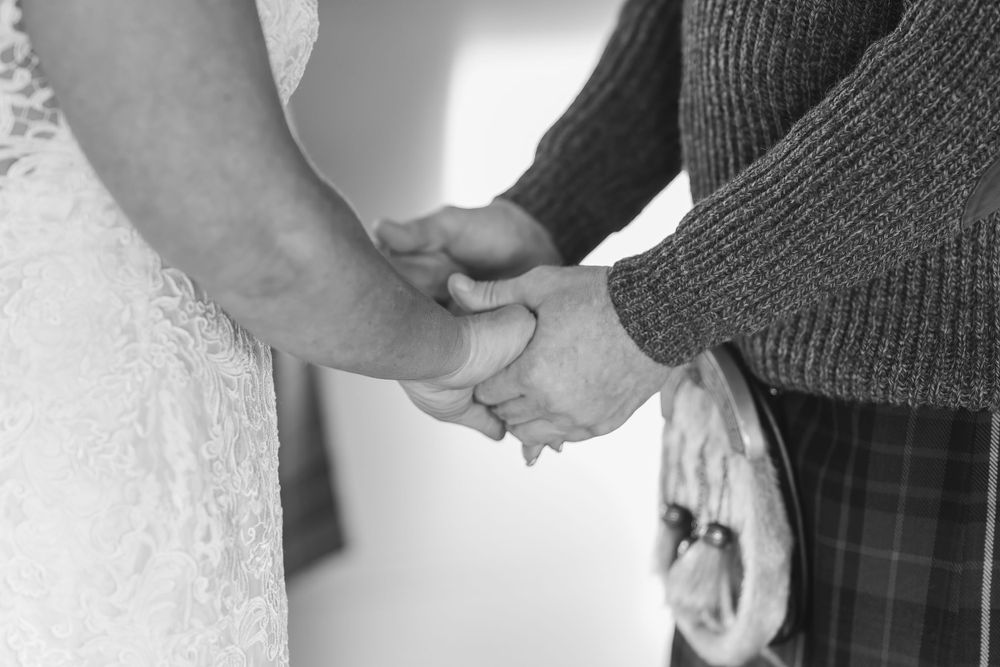 Close-up of wedding couple embracing in traditional Scottish and bridal attire.